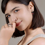 Woman wearing earrings and rings with a neutral background
