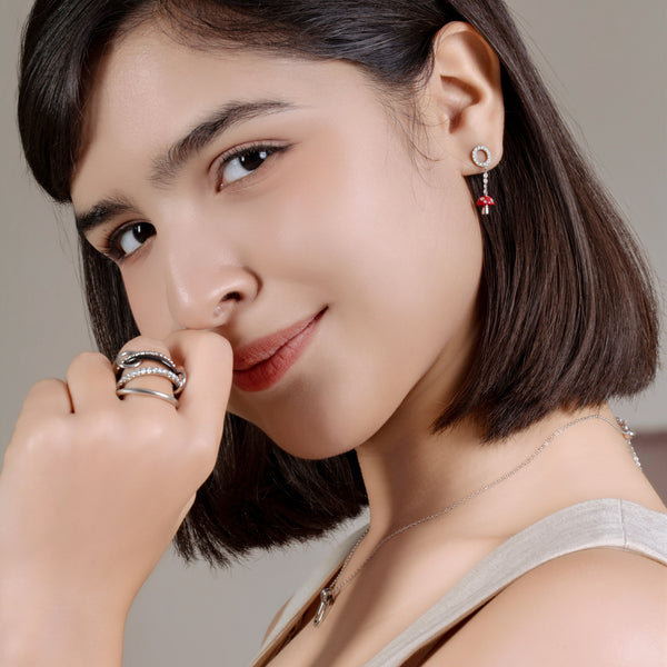 Woman wearing earrings and rings with a neutral background